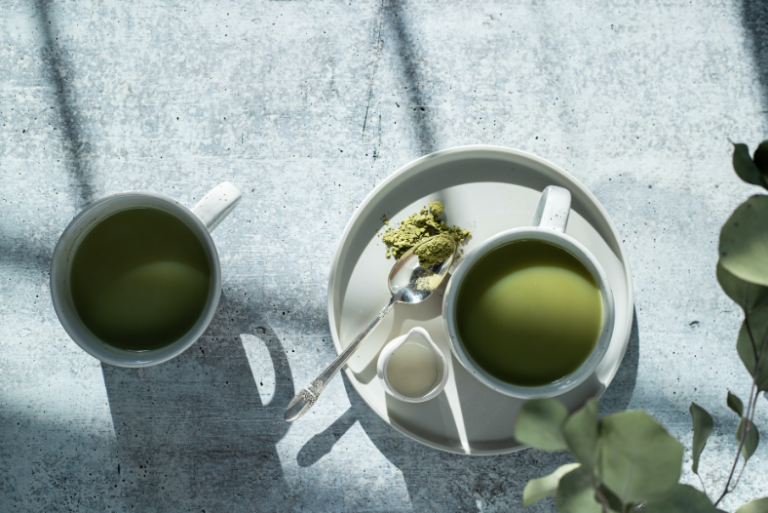 two teacups of matcha on a concrete table